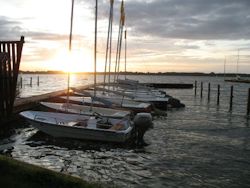 Boote der DJH-Segelschule am Steg beim Sonnenuntergang